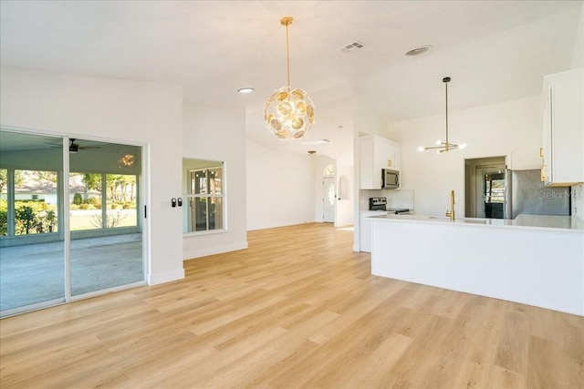 kitchen featuring light hardwood / wood-style floors, white cabinetry, hanging light fixtures, and appliances with stainless steel finishes