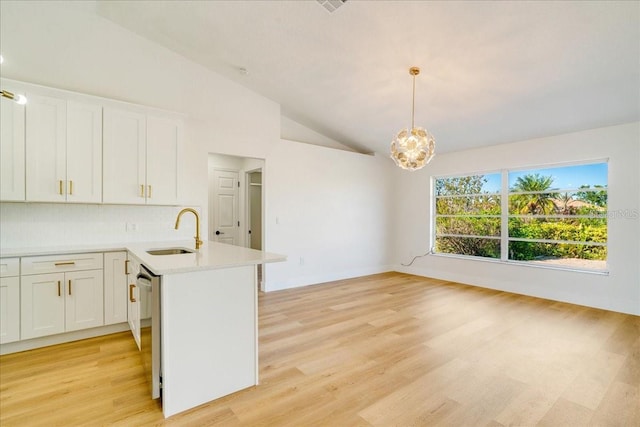 kitchen with white cabinetry, sink, hanging light fixtures, lofted ceiling, and light wood-type flooring