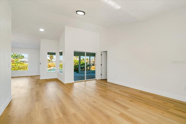 spare room with light hardwood / wood-style floors and a high ceiling