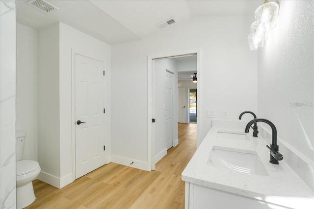 bathroom with ceiling fan, vaulted ceiling, toilet, vanity, and hardwood / wood-style flooring