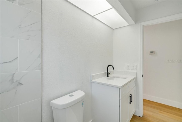 bathroom with hardwood / wood-style floors, vanity, and toilet