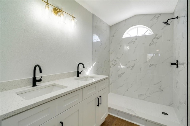 bathroom with hardwood / wood-style floors, vanity, tiled shower, and vaulted ceiling