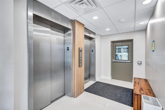 interior space with tile patterned floors, a paneled ceiling, and elevator