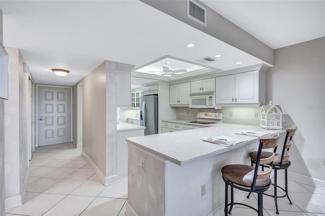 kitchen featuring range with electric cooktop, stainless steel fridge, white cabinetry, kitchen peninsula, and a breakfast bar area