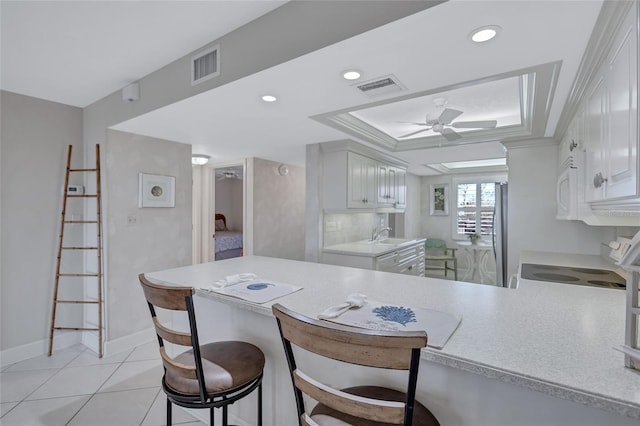 kitchen featuring kitchen peninsula, white cabinets, ceiling fan, and light tile patterned flooring