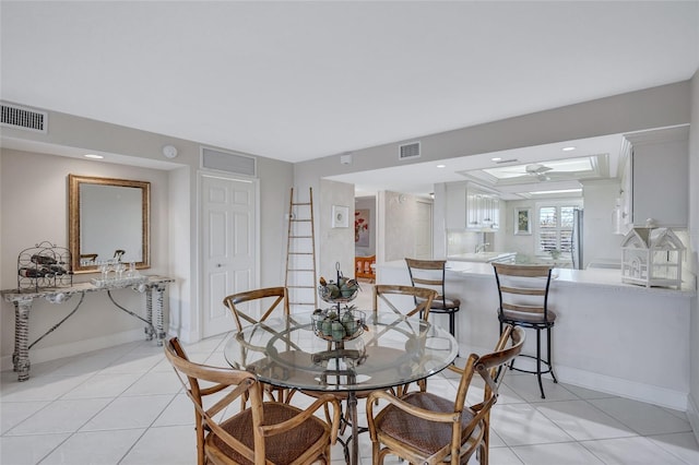 tiled dining area with ceiling fan and sink