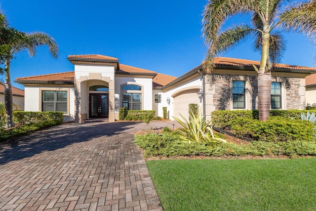 mediterranean / spanish-style house featuring a garage and a front lawn