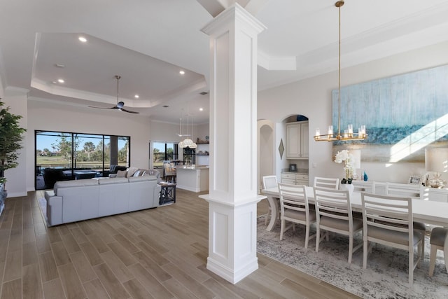 living room featuring a raised ceiling, hardwood / wood-style floors, ceiling fan with notable chandelier, and ornamental molding