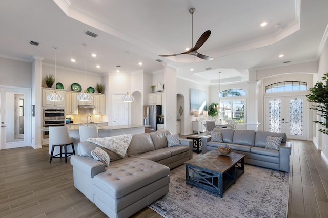 living room with hardwood / wood-style floors, a tray ceiling, ceiling fan, and crown molding