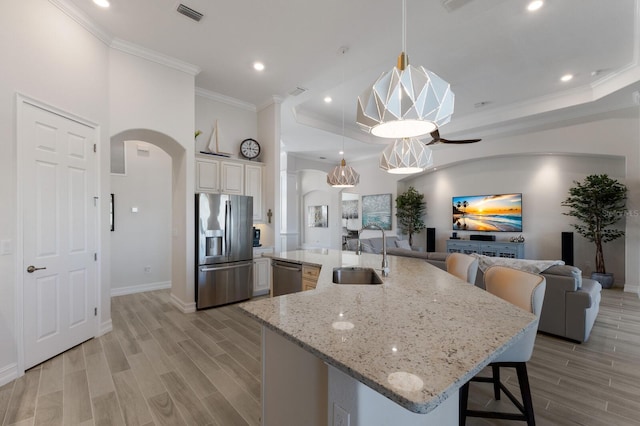 kitchen with pendant lighting, a breakfast bar, sink, light wood-type flooring, and appliances with stainless steel finishes