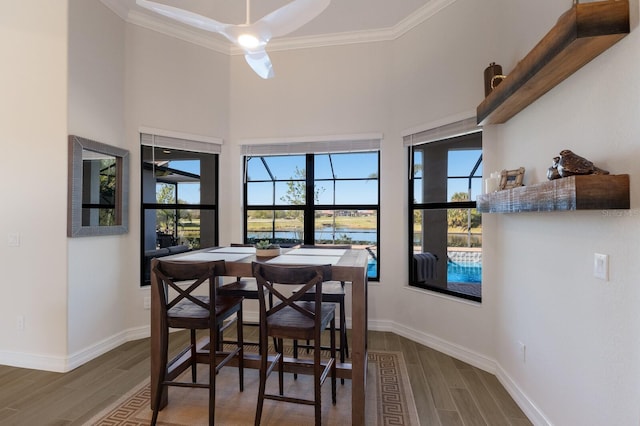 dining area featuring wood-type flooring, a wealth of natural light, and crown molding