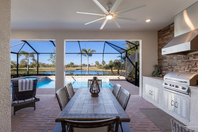 view of patio with glass enclosure, ceiling fan, an outdoor kitchen, area for grilling, and a water view