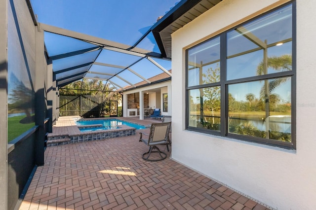 view of patio with a water view, glass enclosure, and a pool with hot tub