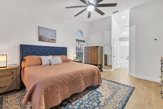 bedroom featuring connected bathroom, light hardwood / wood-style floors, high vaulted ceiling, and ceiling fan