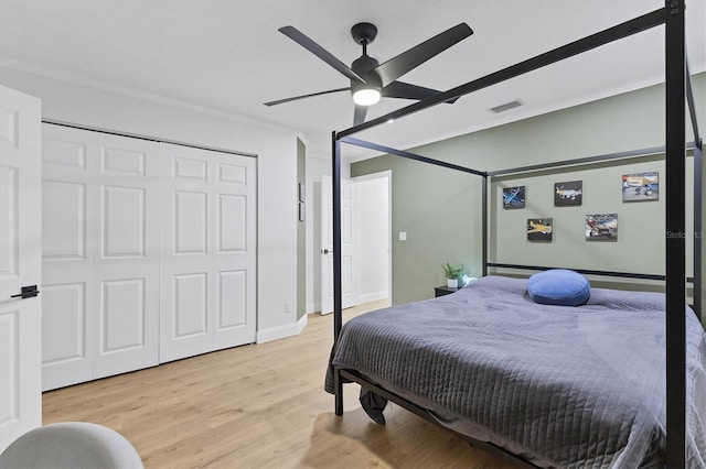 bedroom with ceiling fan, a closet, ornamental molding, and light wood-type flooring