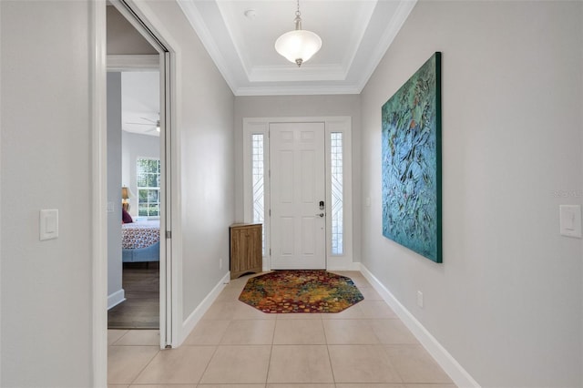 tiled entrance foyer with ceiling fan, ornamental molding, and a tray ceiling