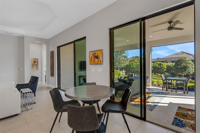 dining room with arched walkways, ceiling fan, light tile patterned floors, and baseboards