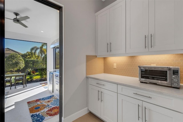 interior space featuring a toaster, light countertops, backsplash, and white cabinetry