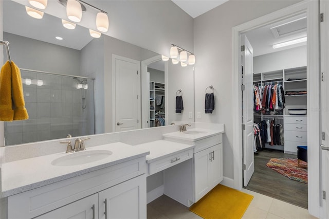 bathroom featuring double vanity, a sink, a walk in closet, and a shower stall