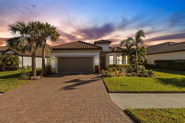 mediterranean / spanish-style house with stucco siding, a tile roof, an attached garage, decorative driveway, and a front yard