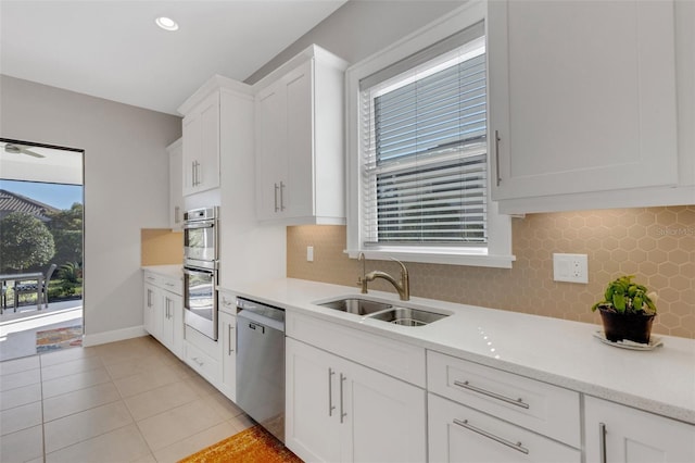 kitchen with white cabinets, appliances with stainless steel finishes, light countertops, a sink, and light tile patterned flooring