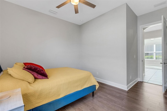 bedroom featuring a ceiling fan, wood finished floors, visible vents, and baseboards