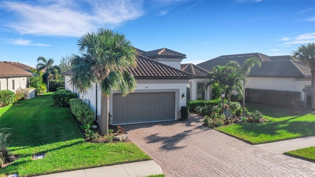 mediterranean / spanish-style house with decorative driveway, stucco siding, an attached garage, a front yard, and a tiled roof