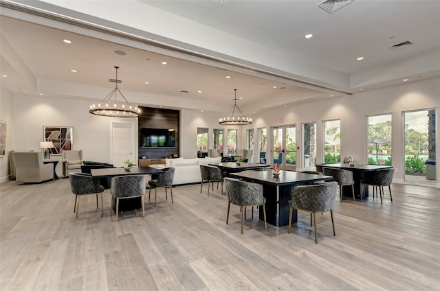 dining room with light wood-type flooring, a raised ceiling, visible vents, and recessed lighting