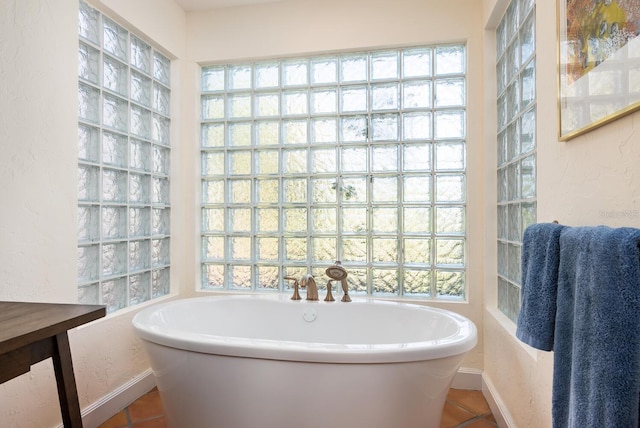 bathroom with tile patterned floors, plenty of natural light, and a bath