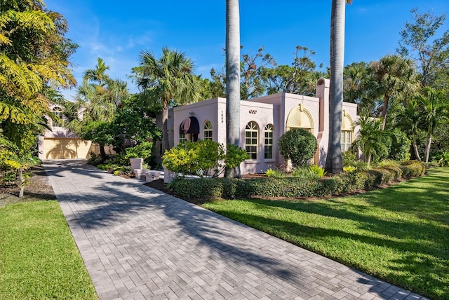 mediterranean / spanish-style home featuring a front lawn, decorative driveway, and stucco siding