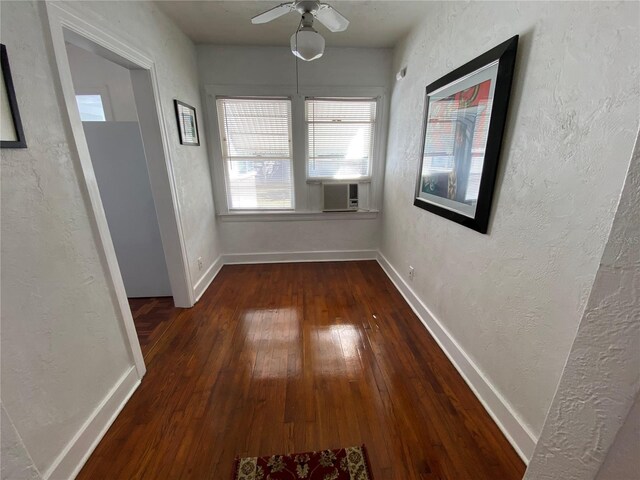 interior space featuring a textured wall, cooling unit, hardwood / wood-style flooring, and baseboards