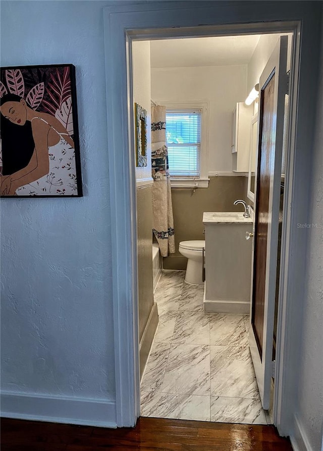 full bathroom featuring baseboards, toilet, marble finish floor, walk in shower, and vanity