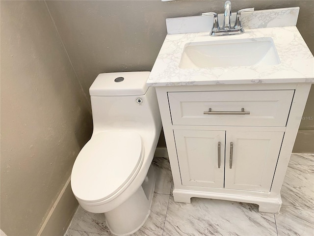 bathroom with a textured wall, marble finish floor, vanity, and toilet