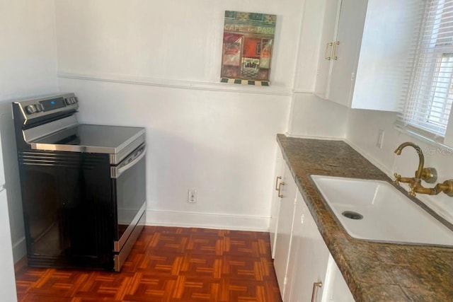 kitchen with baseboards, a sink, stainless steel range with electric stovetop, and white cabinetry