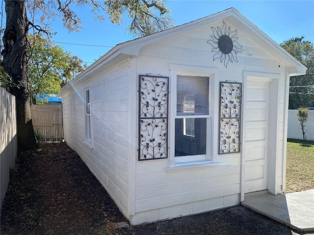 view of side of home featuring an outbuilding and fence