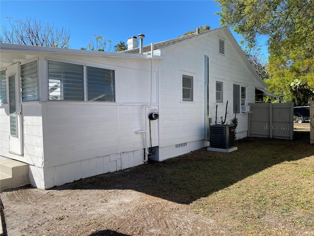 view of side of property featuring crawl space, central AC, and a yard