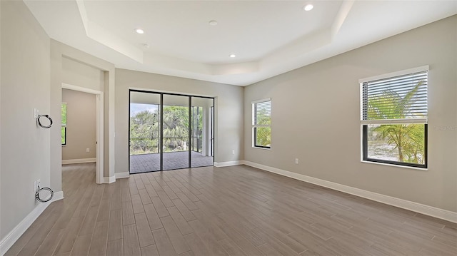 empty room featuring a raised ceiling and light wood-type flooring