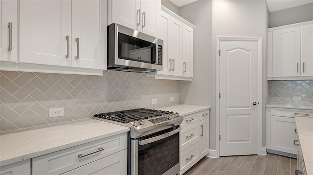 kitchen with white cabinets, light stone counters, appliances with stainless steel finishes, and tasteful backsplash