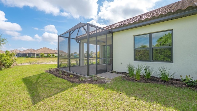 back of house with a lanai and a lawn