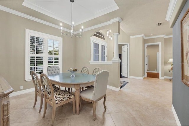 dining room featuring a raised ceiling, ornate columns, an inviting chandelier, and ornamental molding