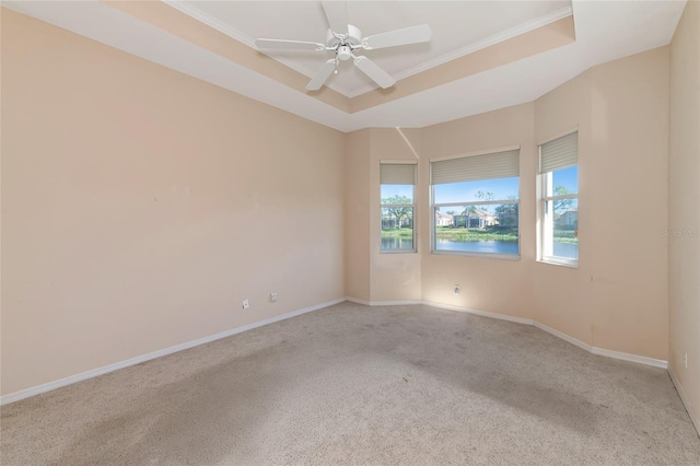 unfurnished room featuring a water view, ceiling fan, ornamental molding, a tray ceiling, and light colored carpet