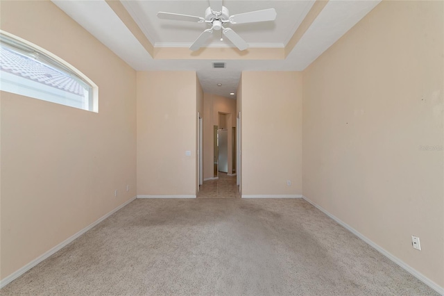 empty room with light colored carpet, a raised ceiling, ceiling fan, and crown molding