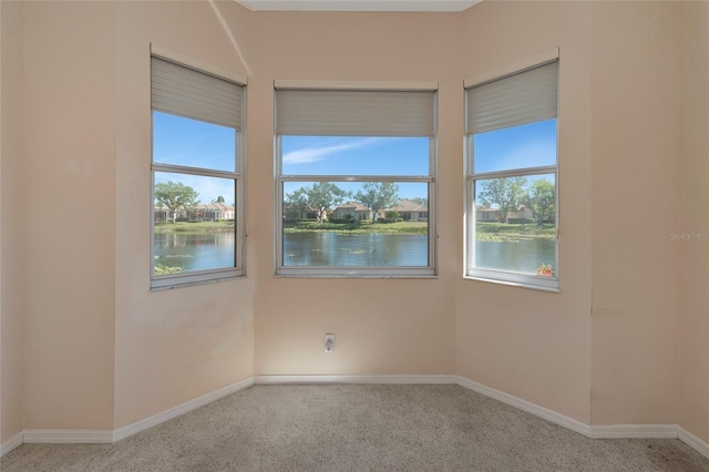 unfurnished room with light carpet and a water view