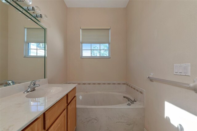 bathroom with vanity and tiled bath