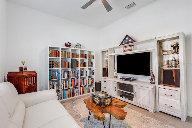 living room featuring ceiling fan, lofted ceiling, and light hardwood / wood-style flooring