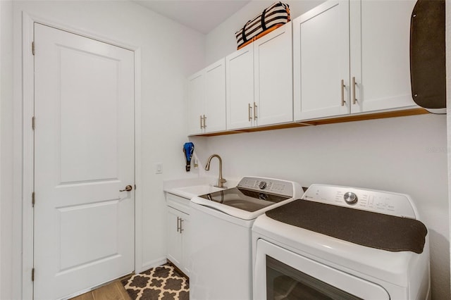 laundry room featuring washer and dryer, light hardwood / wood-style floors, cabinets, and sink