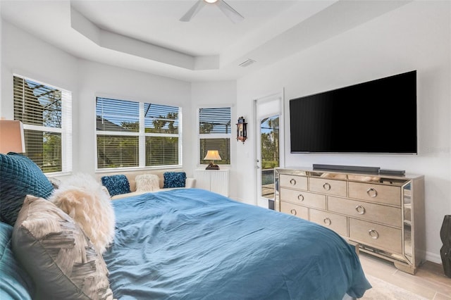 bedroom featuring a tray ceiling, ceiling fan, and light hardwood / wood-style flooring