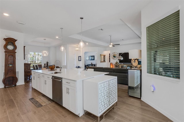 kitchen with dishwasher, a kitchen island with sink, white cabinets, sink, and decorative light fixtures