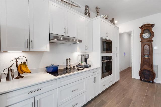 kitchen with white cabinets, oven, black electric cooktop, built in microwave, and wood-type flooring