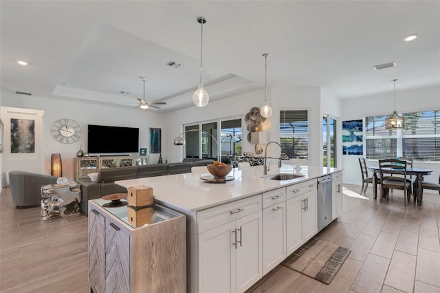 kitchen featuring white cabinetry, ceiling fan, sink, hanging light fixtures, and a center island with sink